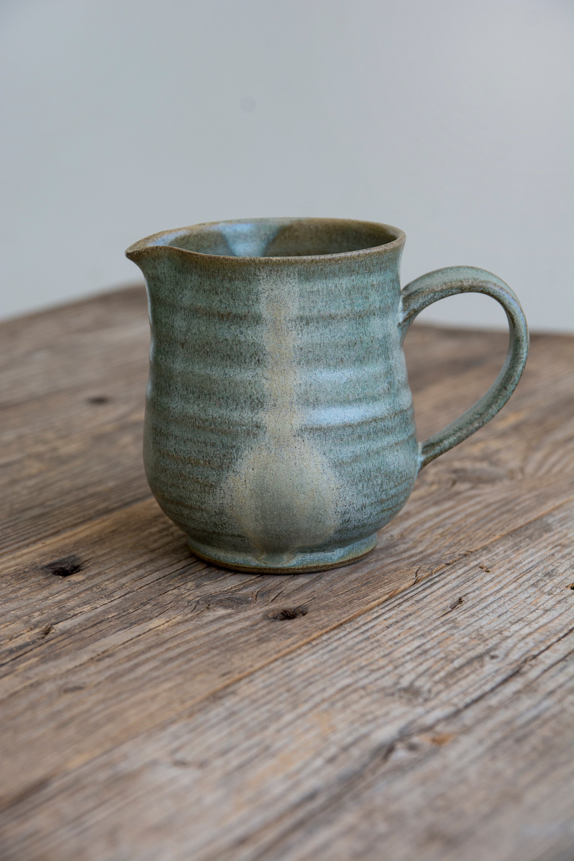 Unique handmade pottery creamer on wooden surface